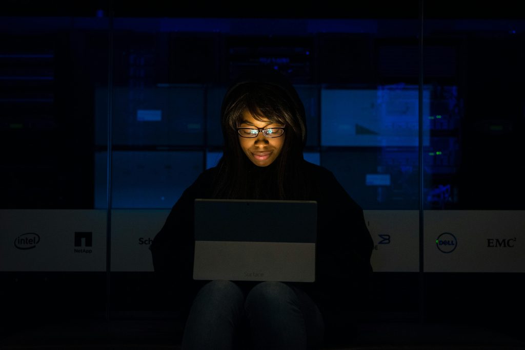 pexels photo 1181330 1181330 A woman uses her laptop in a dimly lit server room, focusing on technology and work.