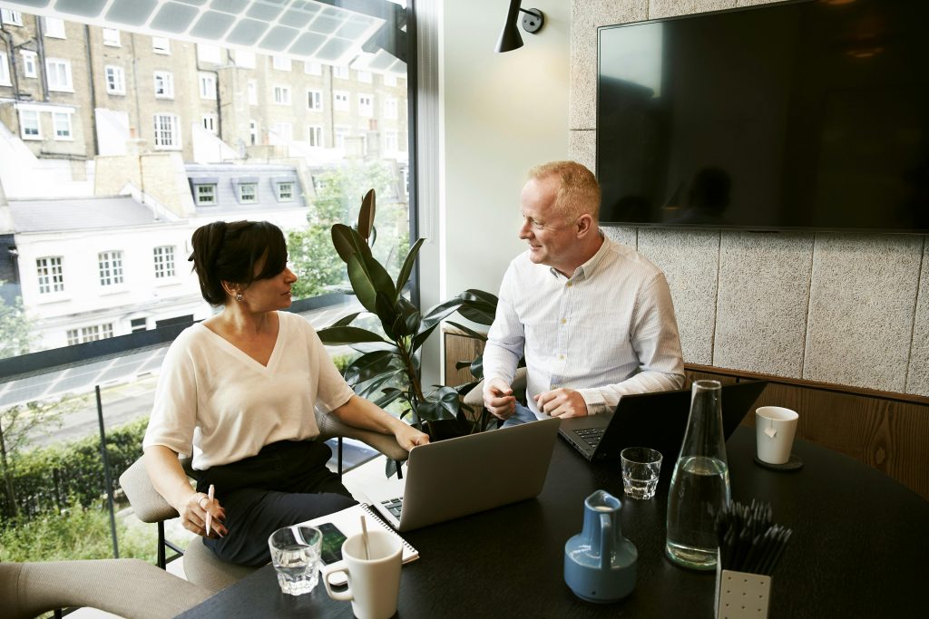 pexels photo 2977565 2977565 Two business professionals engaging in a team meeting in a modern London office with a large window view.